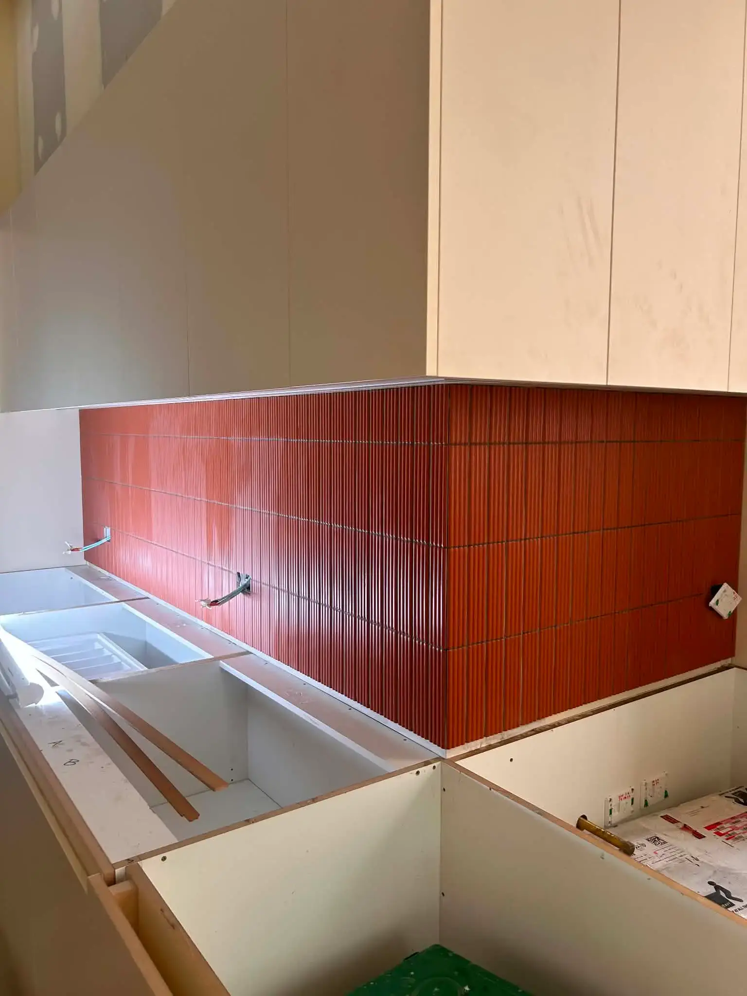 Terracotta fluted tile kitchen splashback wrapping a corner return, with ribs aligned across the join