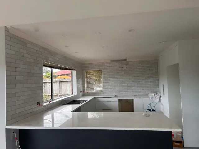 Kitchen with white subway tile splashback running full height around the window and benchtop