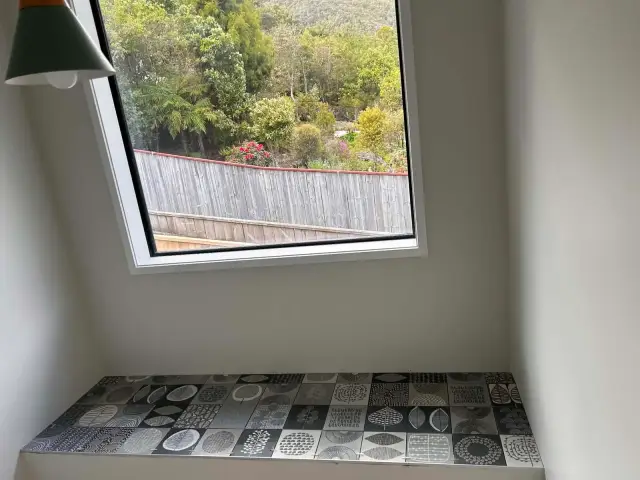 Window seat finished in monochrome patterned tiles, laid to a bush outlook