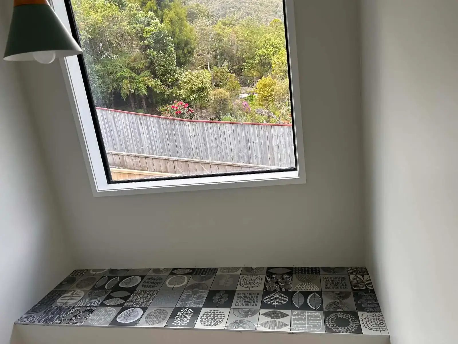 Window seat finished in monochrome patterned tiles, laid to a bush outlook