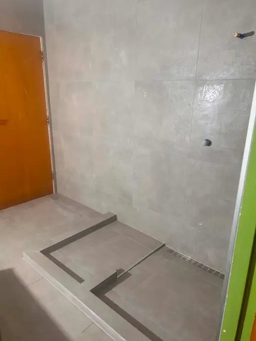 Walk-in shower with grey large-format tiles, tiled hob and linear drain set to fall