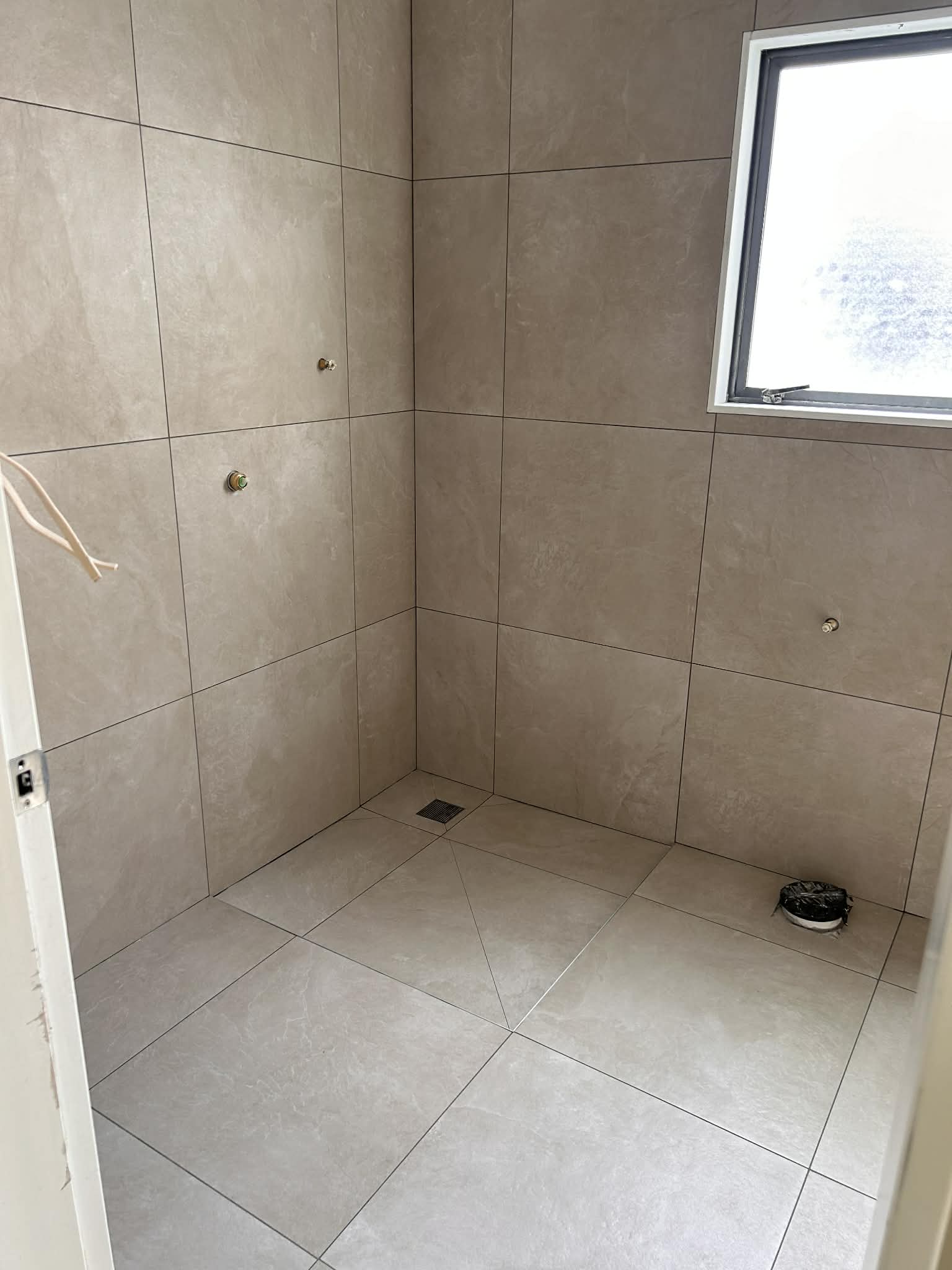 Walk-in shower with large-format beige porcelain tiles — floor-to-ceiling installation in a Wellington home